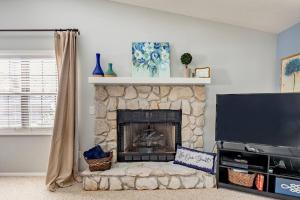 a living room with a stone fireplace with a tv at Creekside Gated Golf Mtn Villa w/fast wifi & paved in Franklin