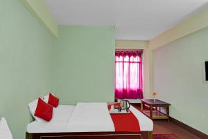 - une chambre avec un lit blanc et une fenêtre rouge dans l'établissement Flagship Evergreen Guest House, à Shillong
