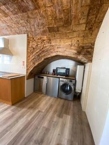 cocina con pared de ladrillo, lavadora y secadora en Casa Antunes en Évora