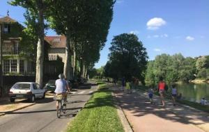 un grupo de personas caminando y montando bicicletas por una calle en Appartement chic proche de Paris, parking inclus, en Saint-Maur-des-Fossés