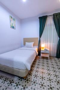 - une chambre avec un grand lit blanc et une fenêtre dans l'établissement BELVA huis, à Bogor