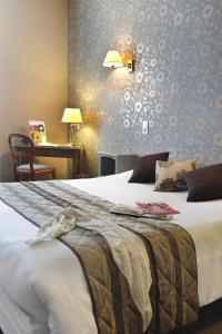 a bedroom with a bed and a desk with a desk at Hôtel Les Tilleuls, Bourges in Bourges