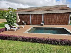 a deck with a pool and two chairs and an umbrella at Private Secured 4 Bedroom Villa in Grand-Baie +13 photos