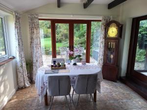 a dining room with a table and some windows at Lane End Cottage in Honiton