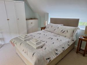 a bedroom with a bed with towels on it at Lane End Cottage in Honiton