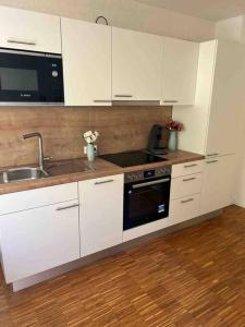 a kitchen with white cabinets and a sink and a stove at Sunset Dreams Apartment in Bühl
