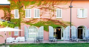 un bâtiment rose avec des volets blancs, des tables et des chaises dans l'établissement Hotel Sant'Andrea, à Ravenne