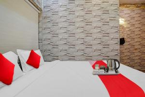 um quarto com uma cama branca e almofadas vermelhas em Flagship Lemon Tree Inn em Rāipur
