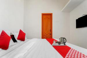a bedroom with a white bed with red pillows at Flagship Cruze Residency in Coimbatore