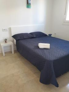 un letto con piumone blu e asciugamano sopra di REYNURBAN a Castillo de Sabinillas