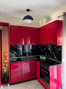 a red kitchen with black counters and red cabinets at Καλλιθεα in Kallithea Halkidikis +2 photos