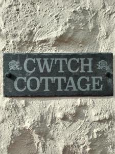 a sign on the side of a brick wall at Cwtch Cottage in Rhondda