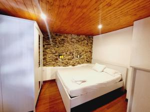 a bed in a room with a stone wall at Precioso Apartamento en Osséja in Osséja