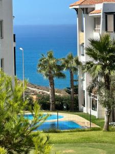 a view of a building and a swimming pool with the ocean at Appartement Asilah Marina Golf in Asilah