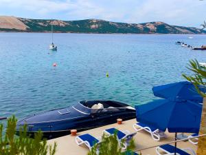 a blue boat on the water with chairs and umbrellas at Villa Olivija-direkt am Strand! in Stara Novalja