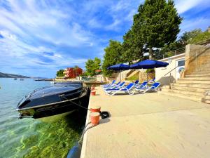 ein Boot neben einem Dock mit Stühlen und Sonnenschirmen in der Unterkunft Villa Olivija-direkt am Strand! in Stara Novalja