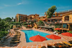 um hotel com uma piscina com guarda-sóis e cadeiras em Rigat Park & Spa Hotel - Adults Recommended em Lloret de Mar