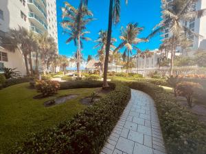 a walkway in a park with palm trees and a building at Oceanview Beachfront Condo on Tides Resort in Hollywood
