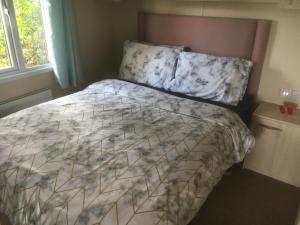 1 cama con edredón y almohadas en un dormitorio en Tim's Getaways Super Caravan A2, Todber Valley Caravan Park, en Gisburn