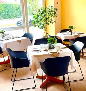 a restaurant with white tables and chairs and a window at Garni Hotel Gartenstadt Erfurt in Erfurt