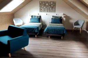- une chambre mansardée avec 2 lits et une chaise dans l'établissement Au Repos du Fayé, à Grosmagny