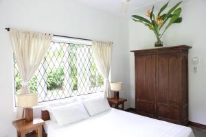 a bedroom with a white bed and a window at Stone Well Garden Villa in Hikkaduwa
