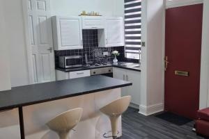 a kitchen with white cabinets and a black counter top at Be our Guest! Stylish-Free parking-Central location in Headingley