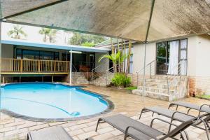 a large swimming pool with chairs and a house at Sapphire Guesthouse in Pinetown
