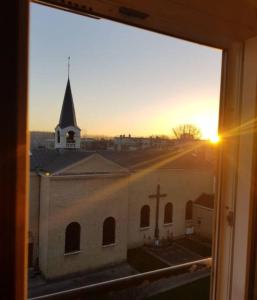 a view from a window of a church with the sunset at Soft Dream- Hyper Centre Dunkerque et Proche Plage 15m in Dunkerque
