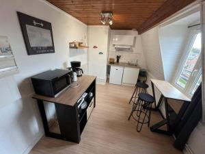 a small kitchen with a microwave and a counter with stools at Soft Dream- Hyper Centre Dunkerque et Proche Plage 15m in Dunkerque