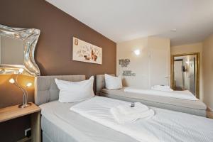um quarto de hotel com duas camas e um espelho em 7o'Clock - Hannover Laatzen em Hanôver