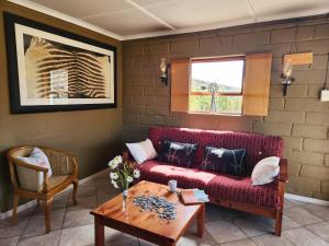 a living room with a red couch and a table at Grootwaterval Guest Farm in Prince Albert