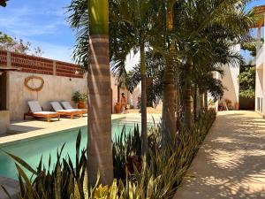 une piscine bordée de palmiers à côté d'un bâtiment dans l'établissement Hotelito Zicatela Cam a la Cruz 70938 Puerto Escondido Oax, à Brisas de Zicatela