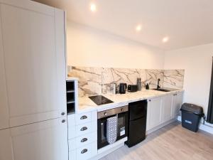 una cocina con armarios blancos y encimeras de mármol en Kaoglen Lodge - Fawn Pod - Hot Tub - Dogs - Pitlochry - Luxury, en Blairgowrie