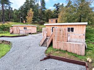 a couple of wooden huts on a gravel road at Kaoglen Lodge - Fawn Pod - Hot Tub - Dogs - Pitlochry - Luxury in Blairgowrie