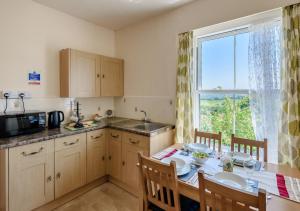 a kitchen with a dining table and a window at Upcott Cottage Upcott House in Barnstaple