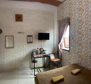 a bedroom with a desk and a tv on a brick wall at Butterfly Kost Tulungagung in Ngantru
