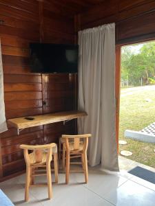 Habitación con escritorio, 2 sillas y TV. en Verde & Mar Chalés, en Penha