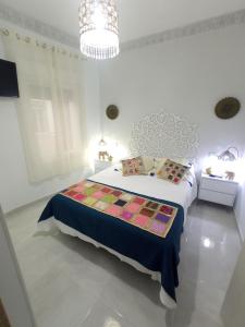 Habitación blanca con cama y lámpara de araña. en Los encantos de Almavir, en Córdoba