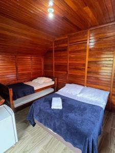 1 dormitorio con 2 camas en una cabaña de madera en Verde & Mar Chalés, en Penha
