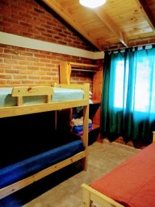 a room with two bunk beds and a brick wall at Cabaña Ángeles del Bosque 5 in Villa Ciudad Parque