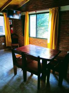 een houten tafel en bank in een kamer met een raam bij Cabaña Ángeles del Bosque 5 in Villa Ciudad Parque