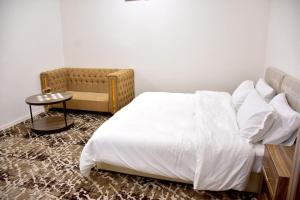 una camera con un letto bianco e una sedia di فندق نجران ول ان a Najran