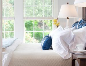 1 dormitorio con 1 cama con almohadas blancas y azules en The Inn At English Meadows, en Kennebunk