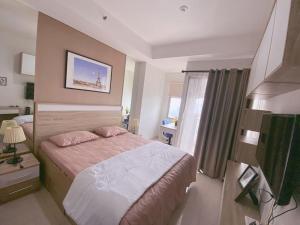 a hotel room with a bed and a window at Apartement Springwood By LiviRooms Tangerang in Warungmangga