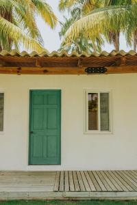une maison avec une porte verte et une terrasse en bois dans l'établissement Los Olivos La Playa Hotel y Restaurante, à Escuintla