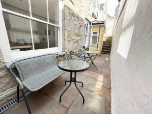 un patio con banco, mesa y ventana en Spacious Home Near Seafront & Train Station 5 Bed Sleeps 10- Central Penzance en Penzance