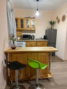 a kitchen with a wooden counter and two green bar stools at Aizkraukles studio tipa dzīvoklis in Aizkraukle