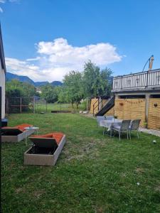a yard with two tables and chairs in the grass at Entre lac et montagne in Cluses