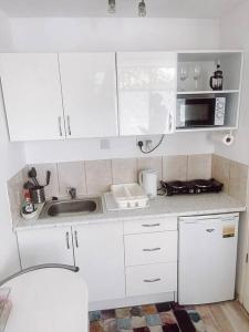 a white kitchen with a sink and a microwave at 2 bed London Studio Flat, Fully Equipped. in Croydon
